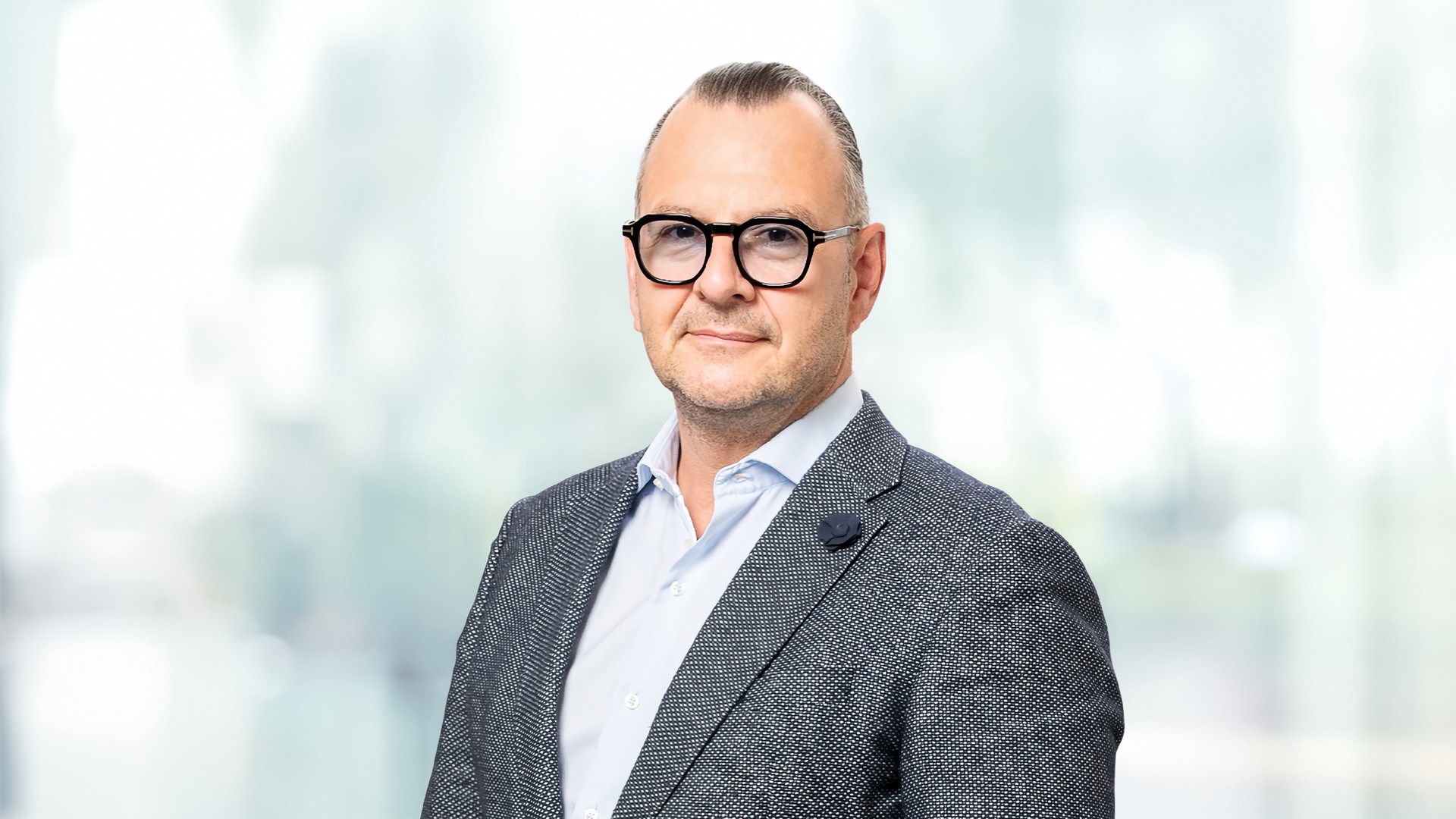 Ing. Paul Eichberger im Querformat, Brustbild mit dunkler Brille, grauem Sakko und hellblauem Hemd vor einem hellen, unscharfen Hintergrund.